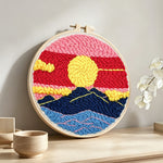Finished sun over mountains with pink and red sky artwork displayed on a wall